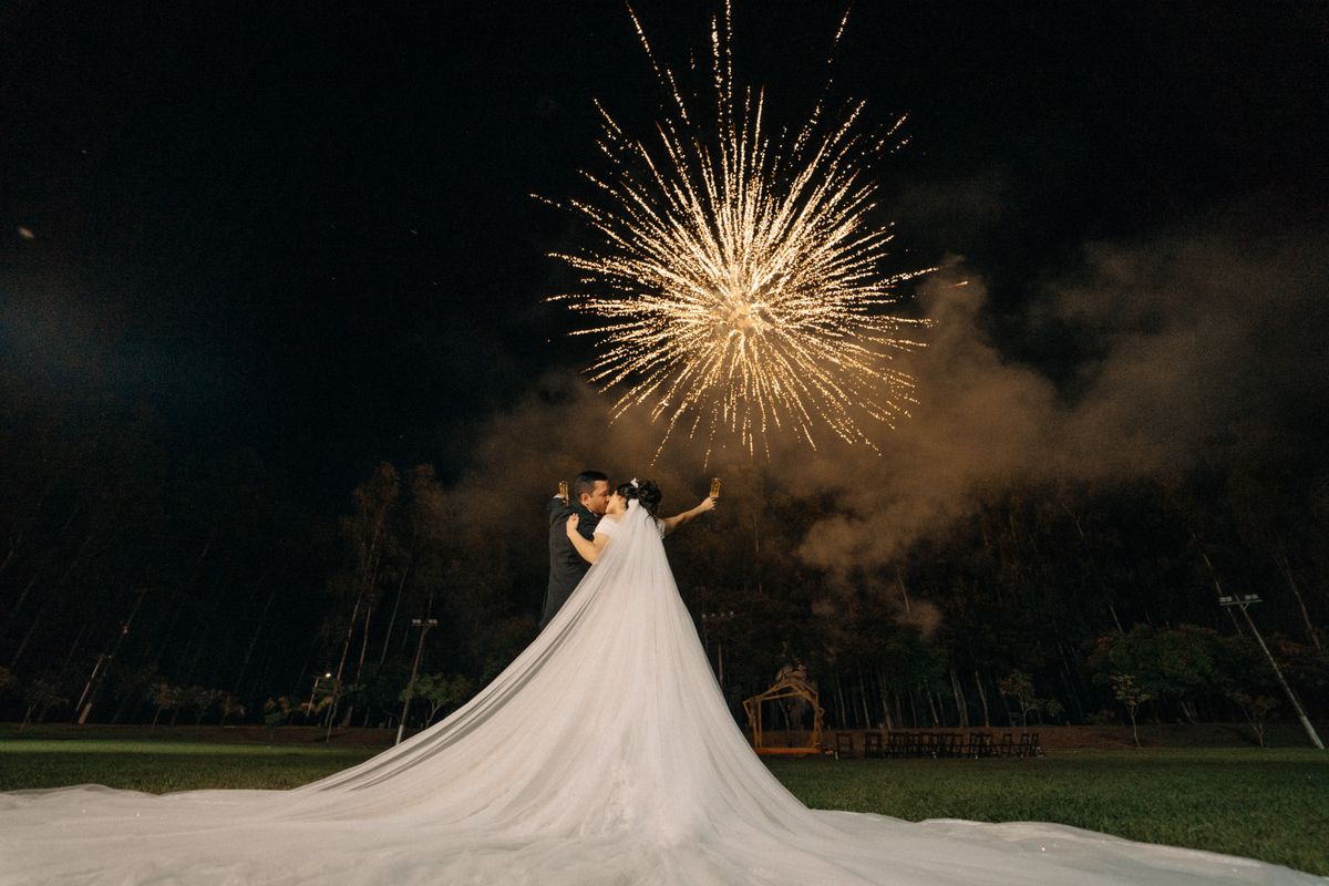 A couple shares a tender moment as fireworks light up the night sky, celebrating their wedding outdoors.