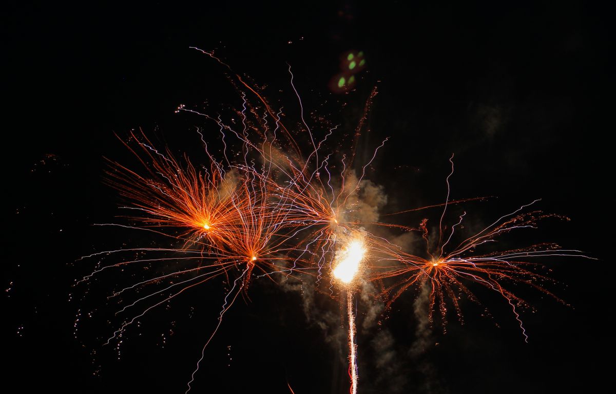 Vibrant fireworks burst against a dark night sky, showcasing colorful light trails.