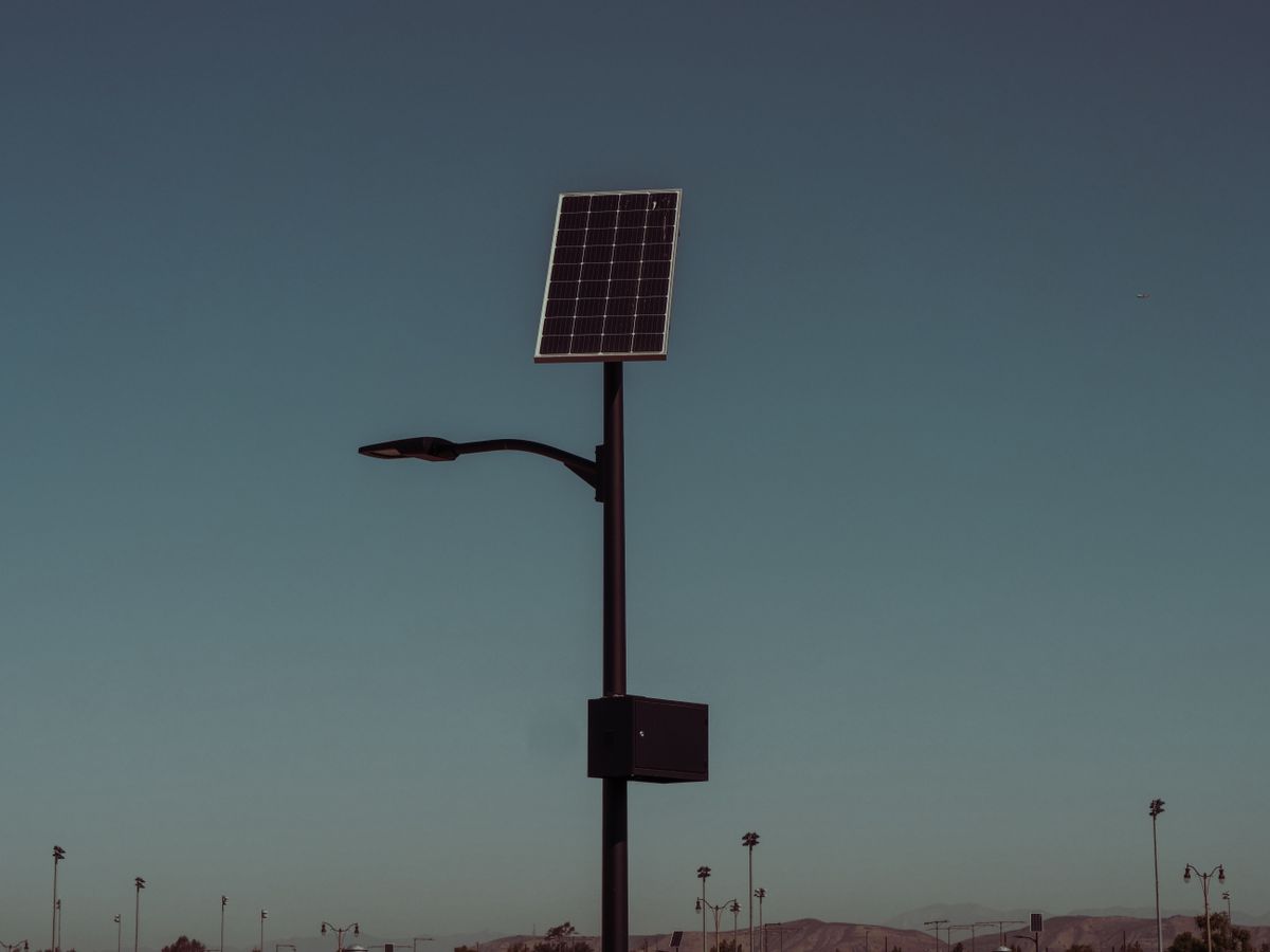 Street light with solar panel against a dusky sky, symbolizing renewable energy.