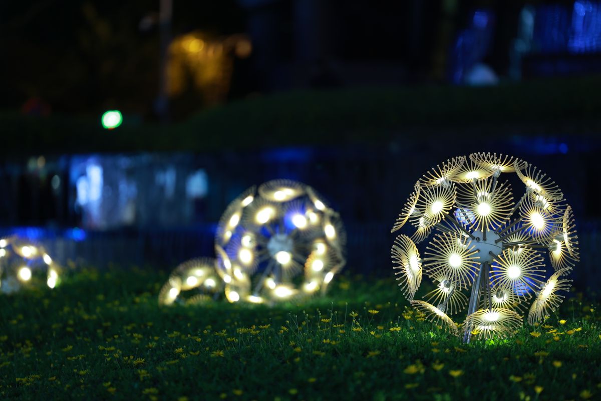 Artistic glowing spheres illuminate a garden at night, creating a magical atmosphere.