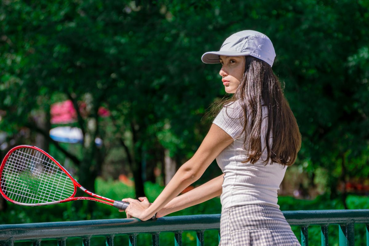 Portrait of a woman in sportswear holding a tennis racket outdoors.