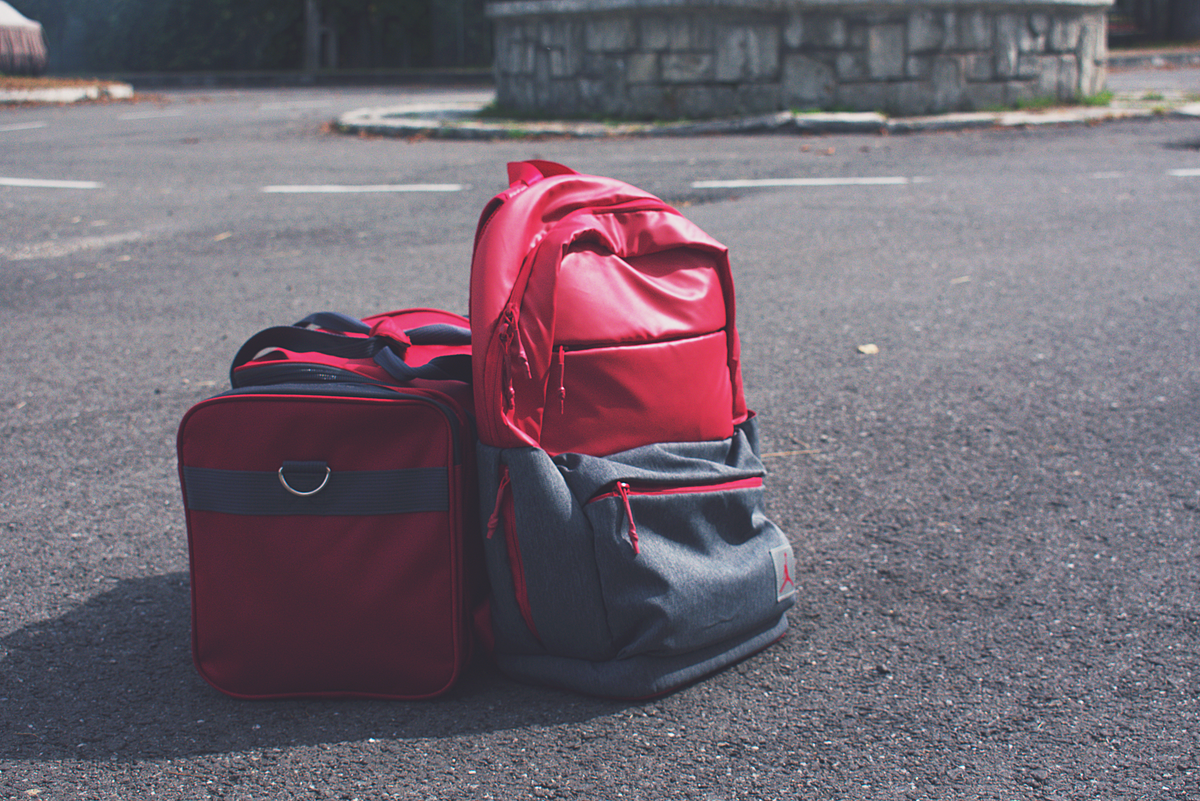 Red backpack and matching bag on asphalt, perfect for travel themes.