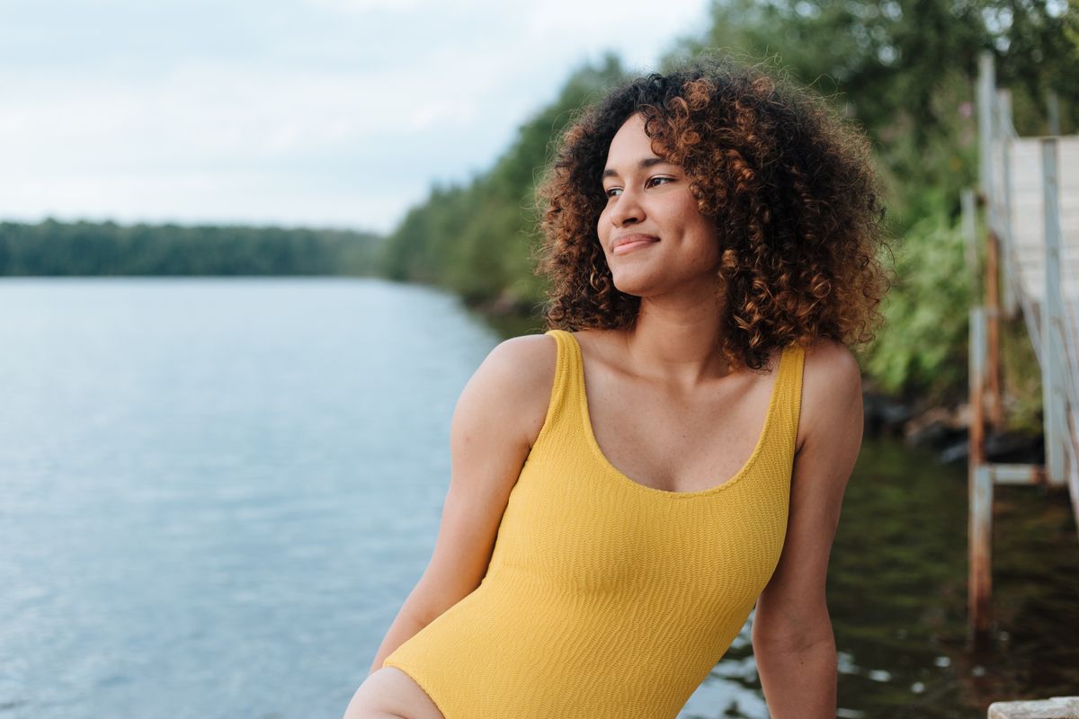 Peaceful moment of a woman sitting by a lake, enjoying the summer breeze.