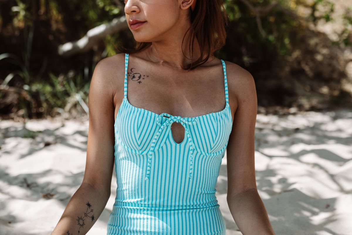 A young woman in a blue striped top enjoys the sunny beach atmosphere.