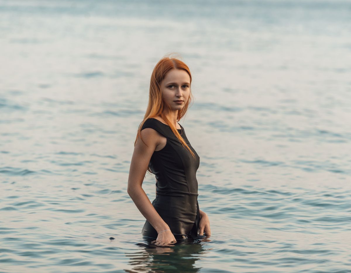 Portrait of a woman standing in the sea wearing a black swimsuit in Гагра.