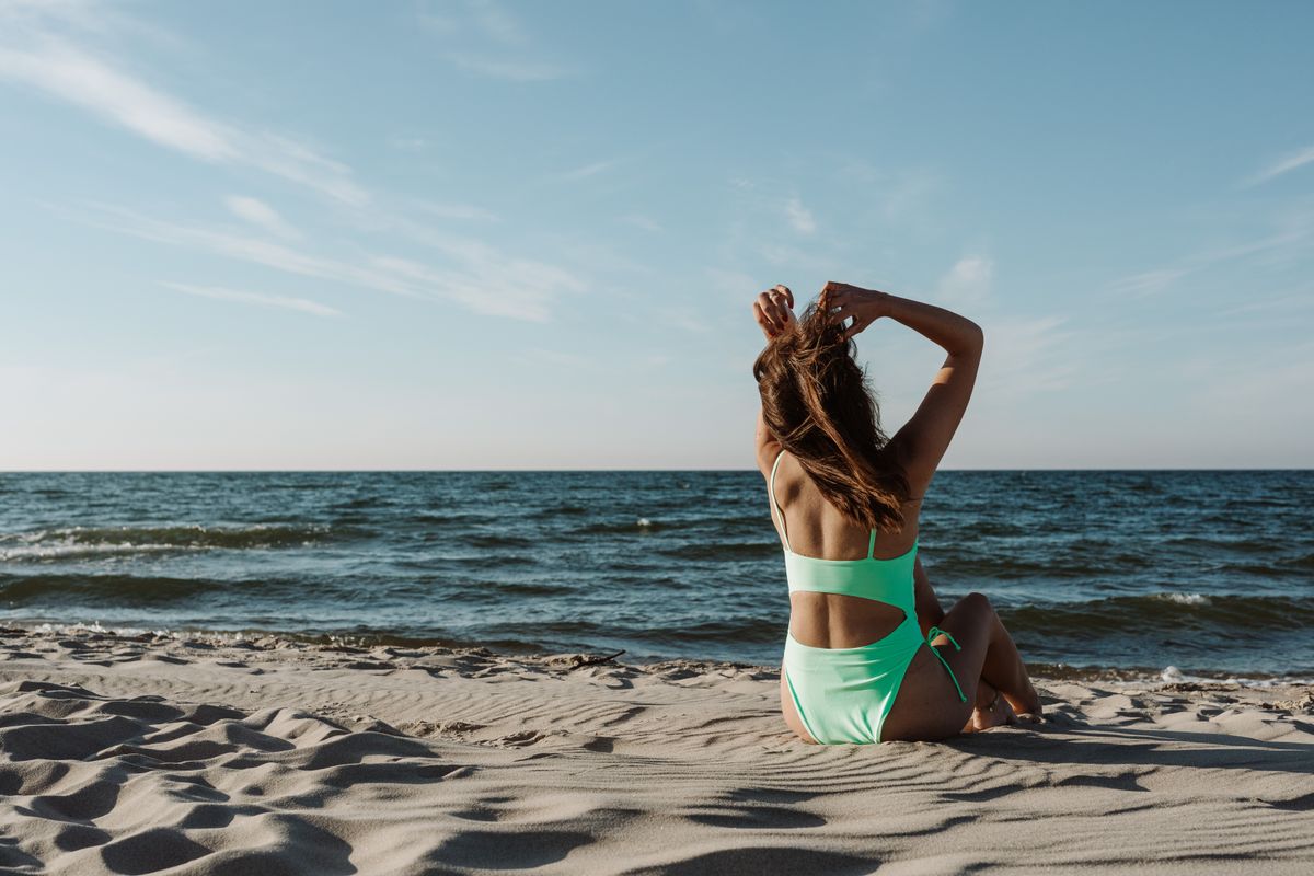 Woman in swimsuit enjoying relaxation on a sunny beach by the sea.