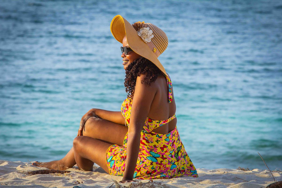 Woman in colorful dress and sun hat enjoying the beach in Dar es Salaam, Tanzania.
