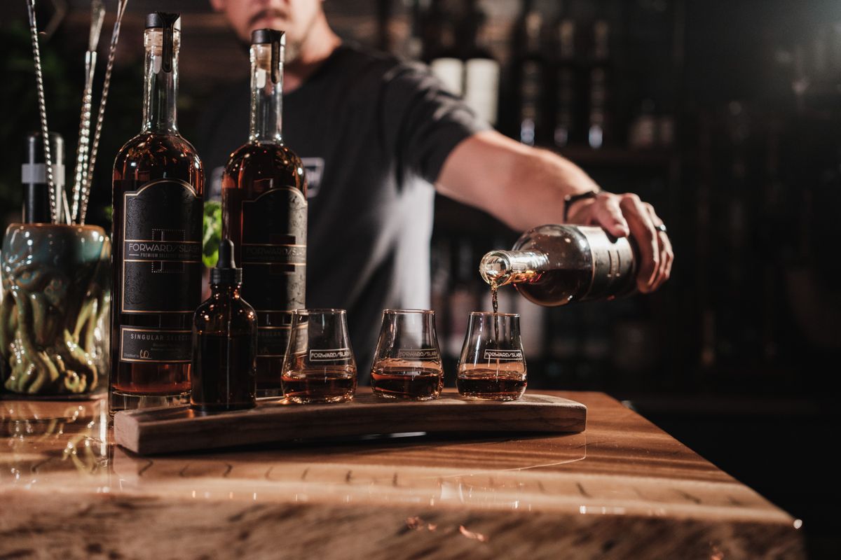 A bartender skillfully pouring whiskey into glasses on a wooden bar in a cozy pub.