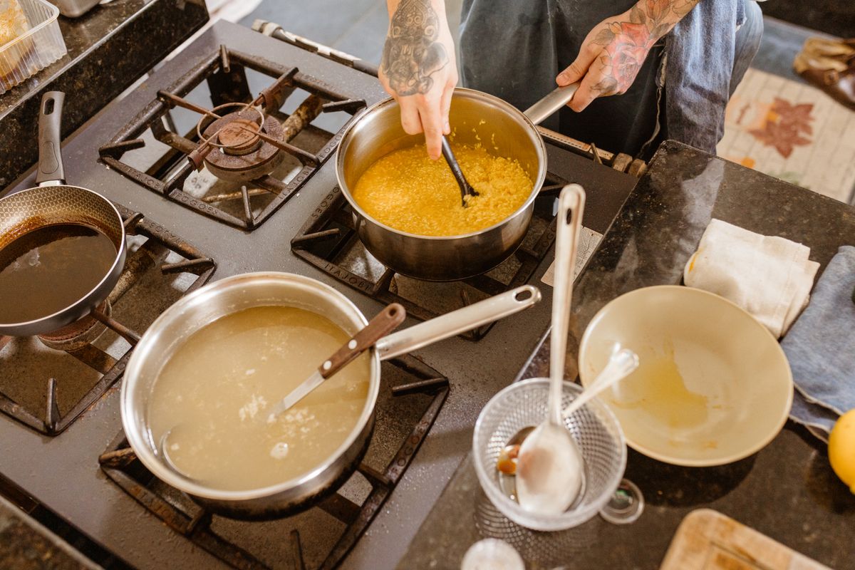 Professional chef stirring ingredients on a gas stove in a modern kitchen setting, showcasing skillful culinary preparation.