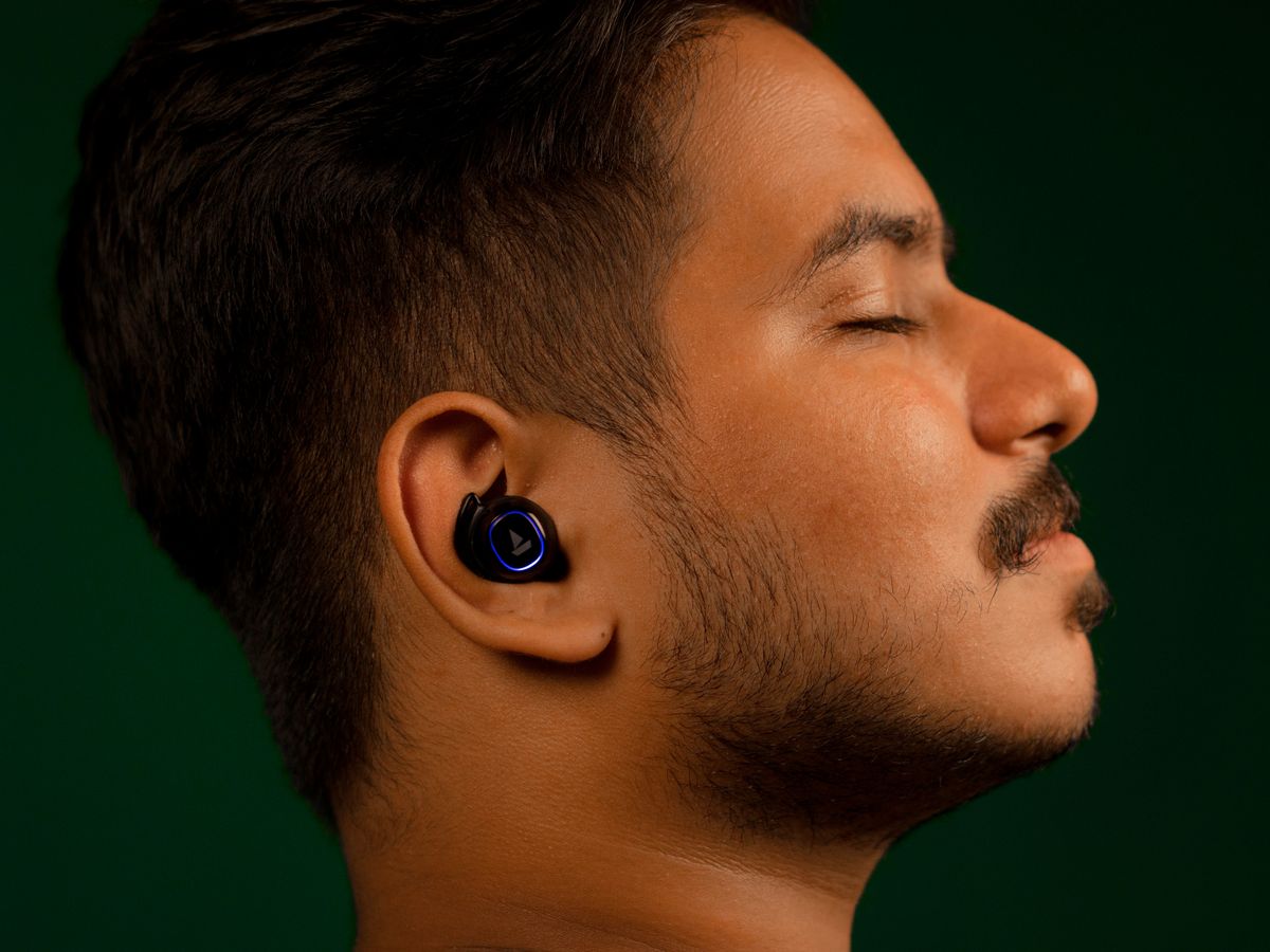 Close-up of a man listening to music with earbuds, eyes closed, serene expression.