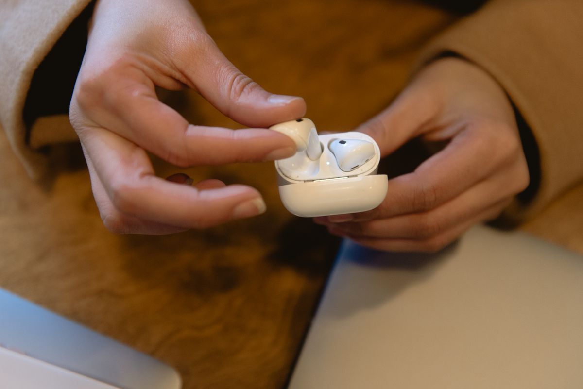 Person holding wireless earbuds, showcasing modern tech and design.