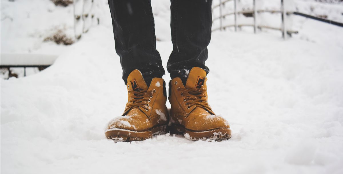 Feet in yellow boots standing on fresh snow, showcasing winter fashion.