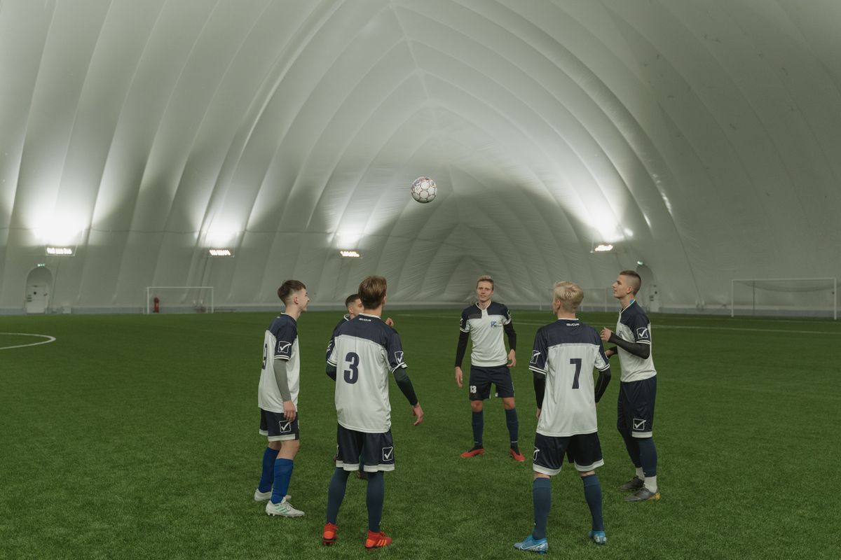 A soccer team practicing indoors, players in blue and white uniforms focusing on ball control.
