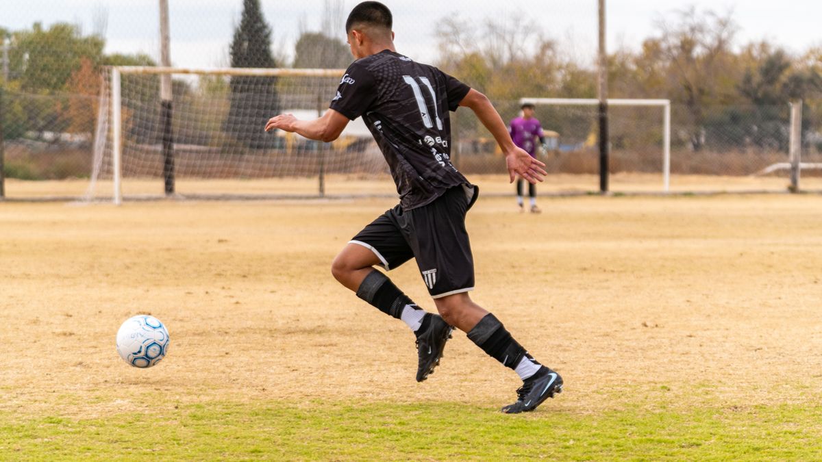 Soccer player dribbling the ball during a match on an outdoor field.