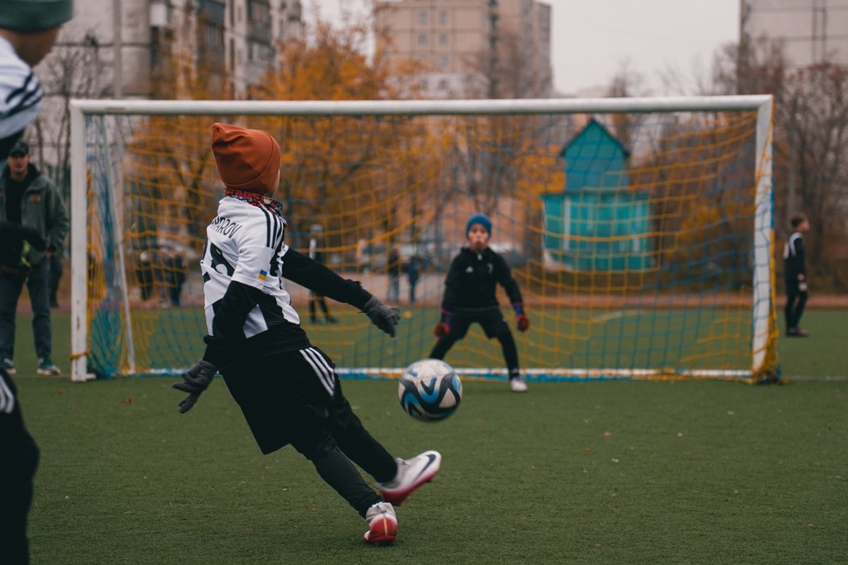 Children playing soccer on a cool autumn day in a park in Kyiv, Ukraine, enjoying outdoor sports.