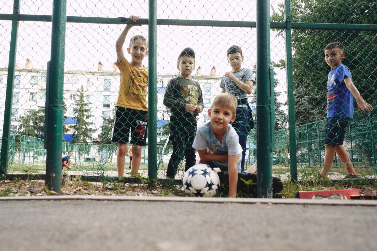 A group of boys playing with a soccer ball outdoors at a playground.