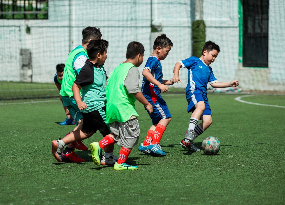 A group of boys energetically playing soccer outdoors on a sunny day in Vietnam.