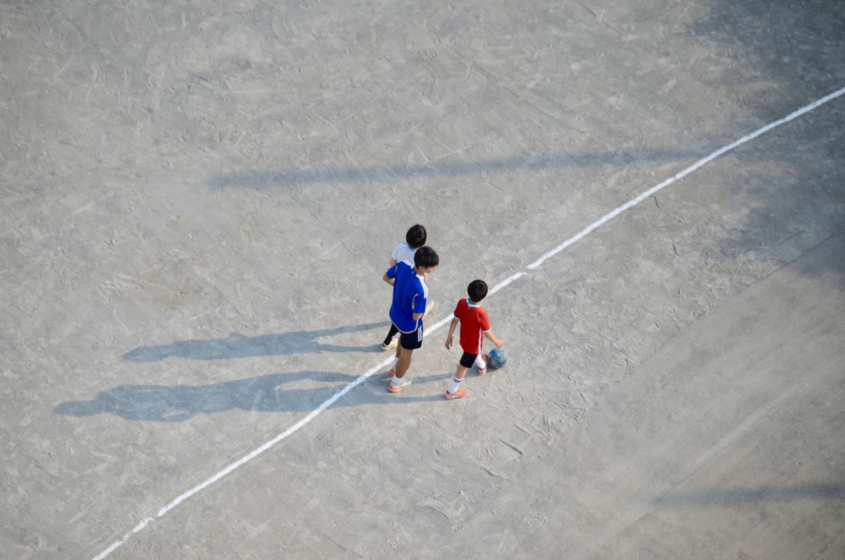 Children playing soccer on an outdoor field, aerial view.