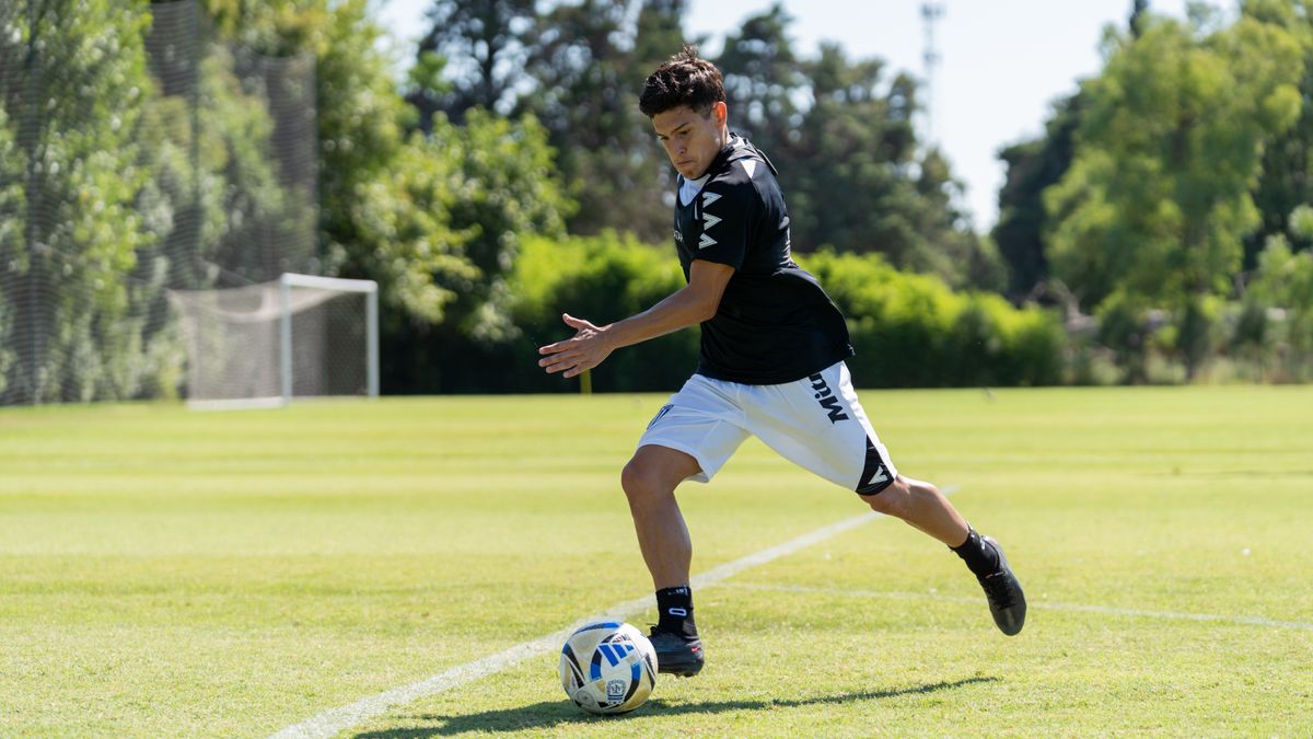 A young athlete skillfully dribbles a soccer ball on a sunny field, showcasing agility and determination.