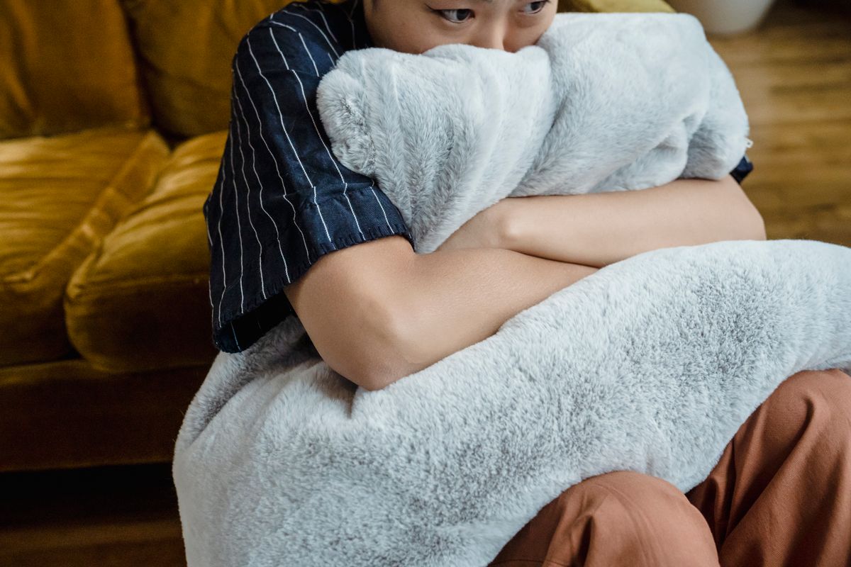 Person embraces a soft faux fur pillow indoors, exuding comfort and warmth.