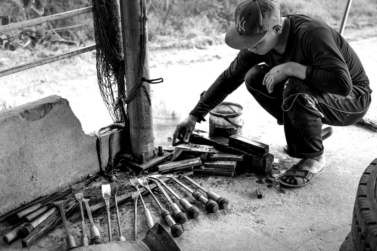 A craftsman working with chisels and tools outside on a sunny day.