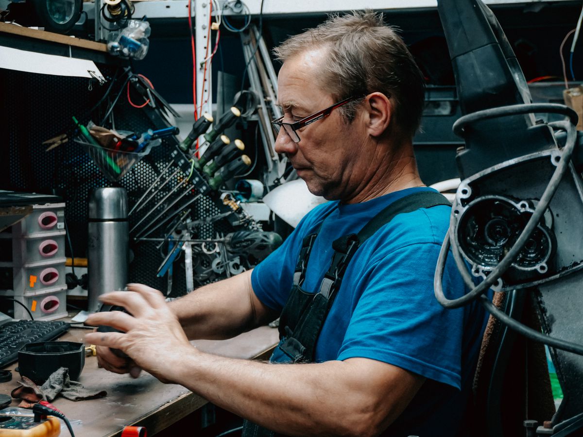 An experienced craftsman focused on work in a well-equipped garage workshop with tools and machinery.