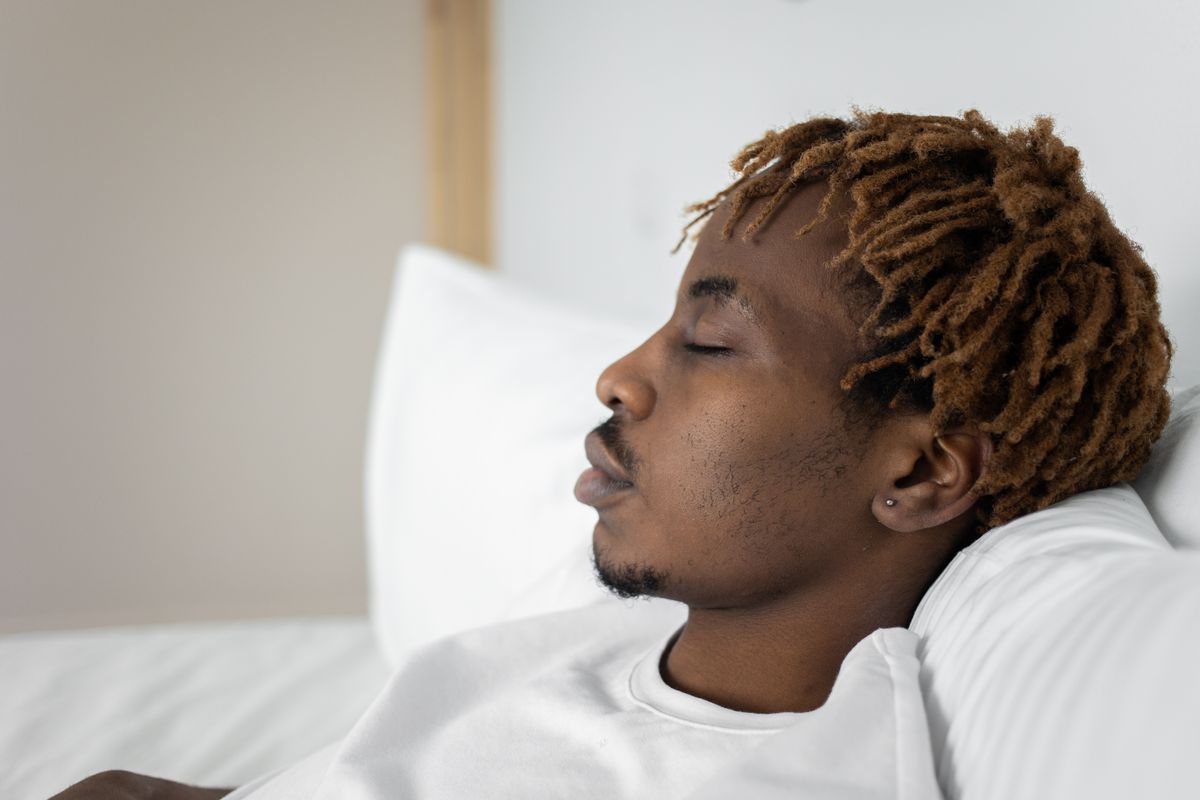 Close-up of a young man sleeping in bed, capturing a serene moment of rest and relaxation.