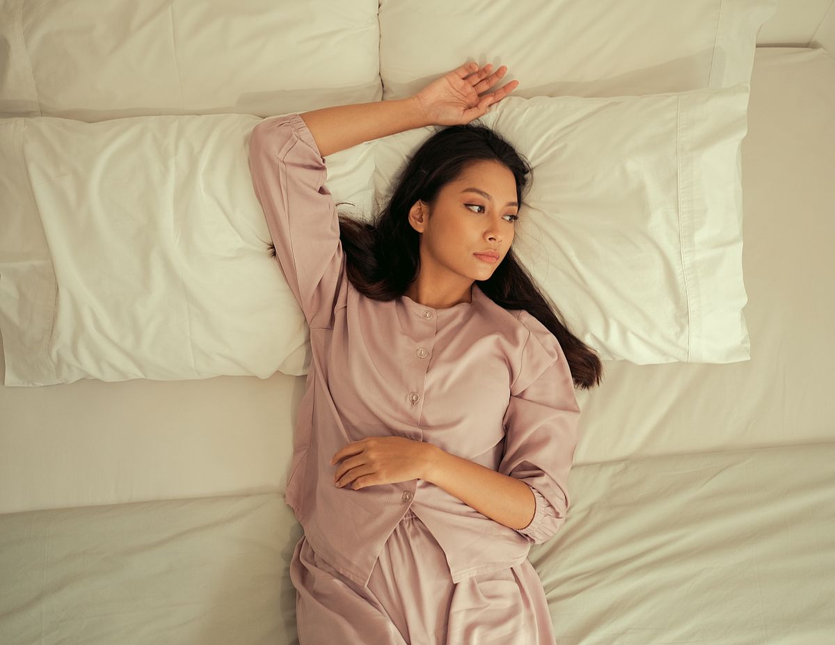 Woman relaxing on a bed in comfortable pajamas, enjoying leisure time indoors.