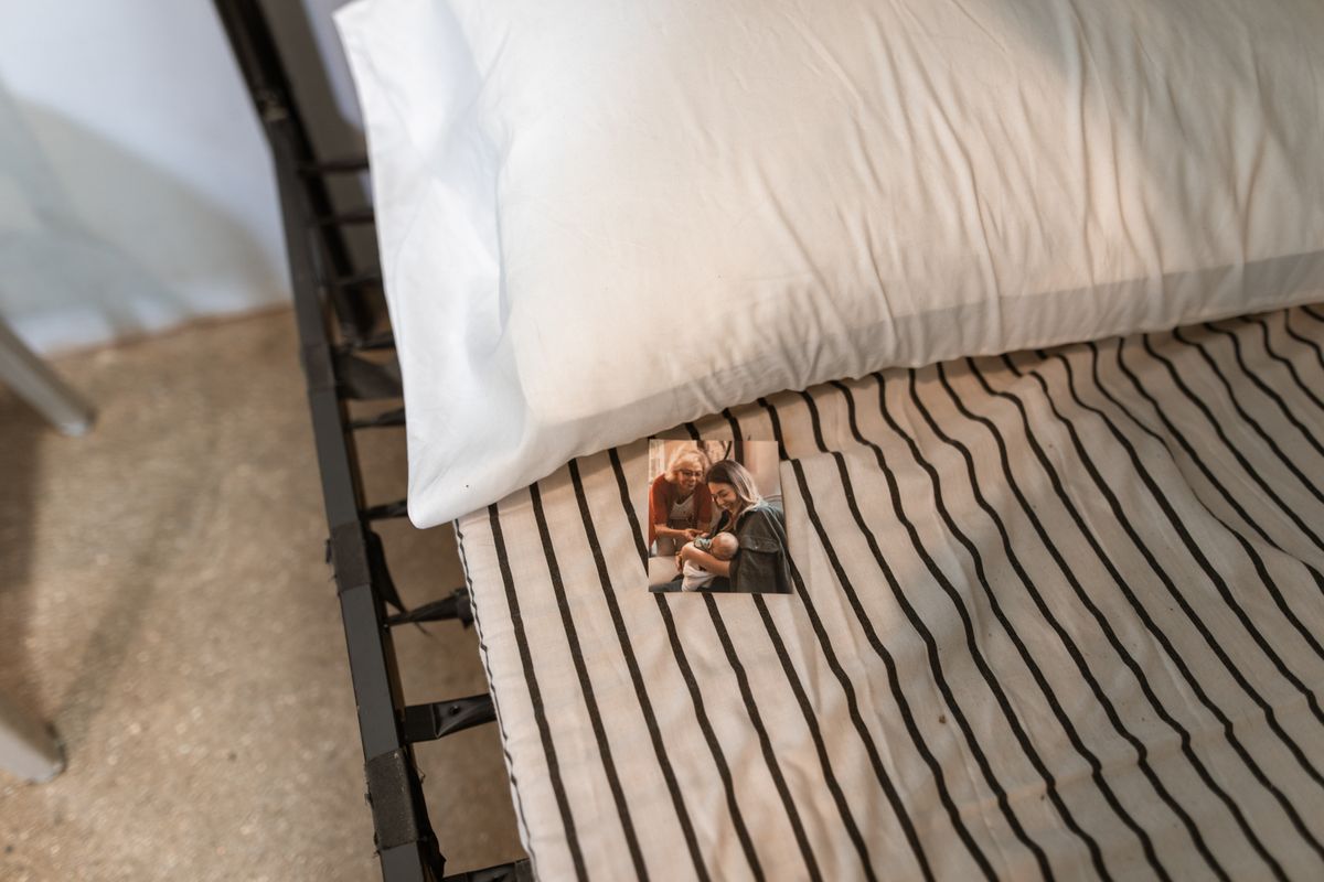A high angle shot of a bed with striped sheets, a pillow, and a family photo.