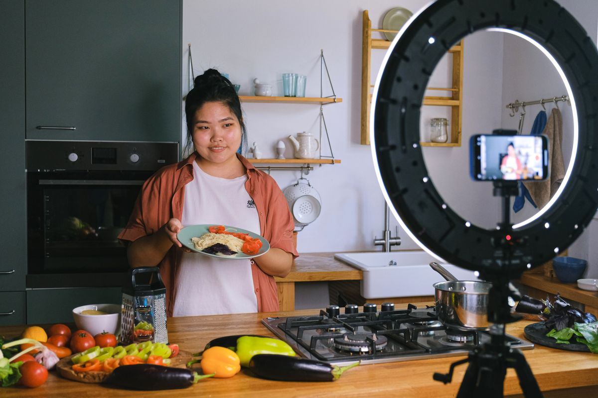 A woman demonstrates cooking in a stylish kitchen while filming content. Perfect for culinary and lifestyle themes.