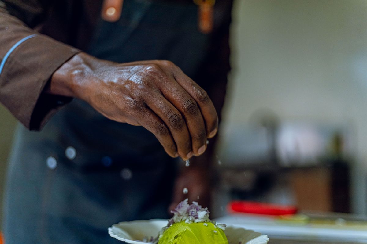 Close-up of a chef seasoning an avocado dish, adding a touch of culinary art to gourmet cooking.
