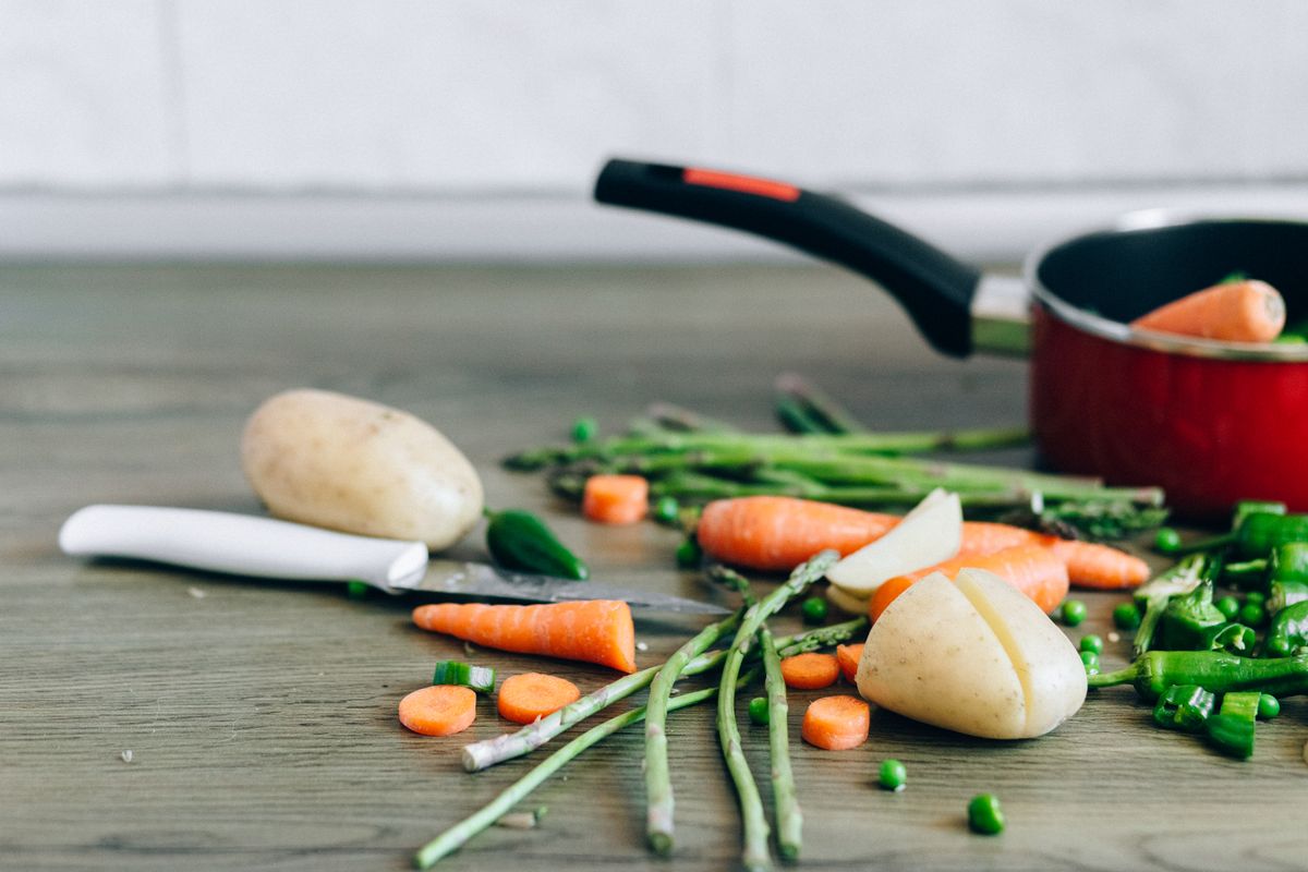 A selection of fresh vegetables with a knife on a wooden surface, perfect for healthy cooking and food preparation.