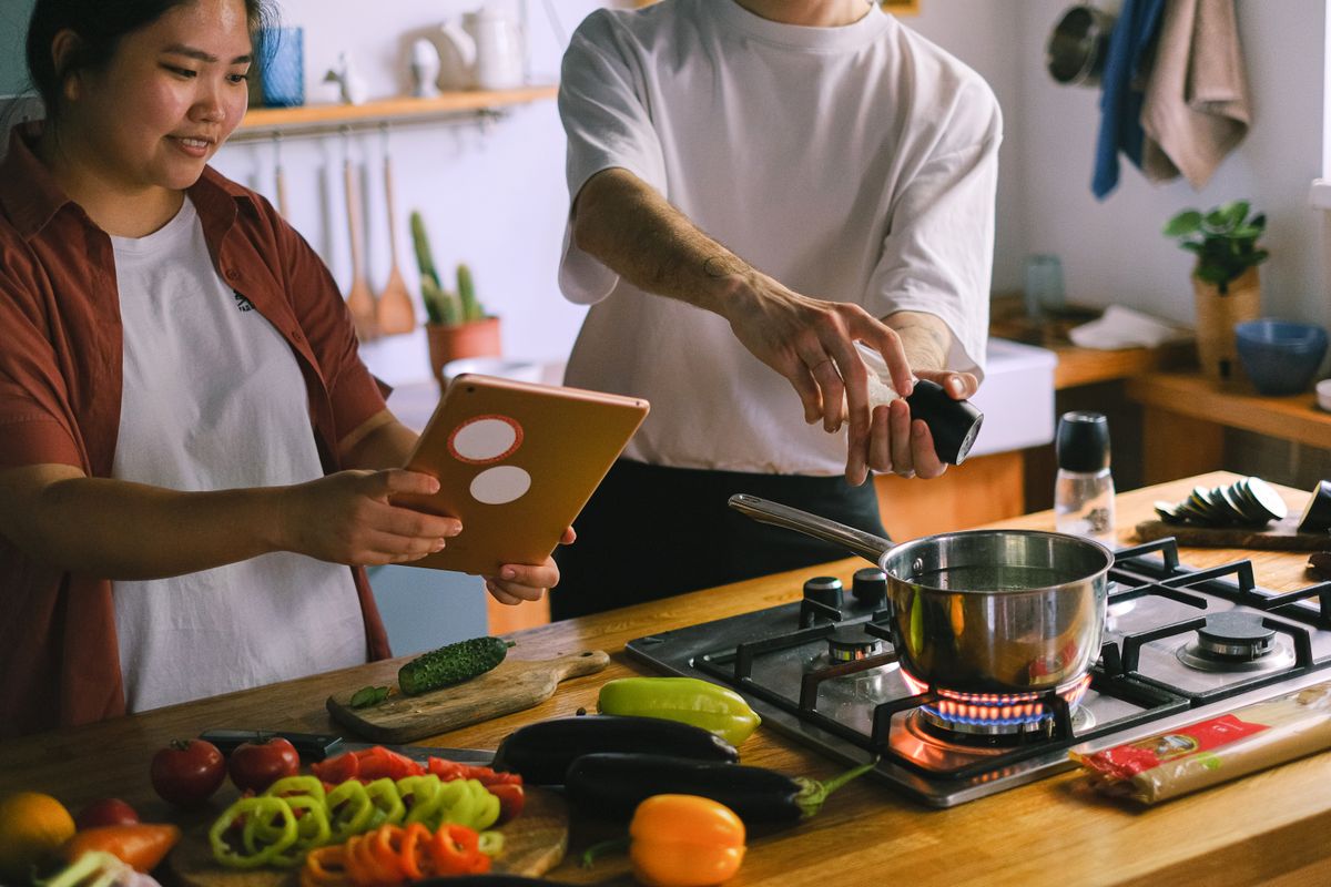 A happy couple using a tablet while preparing a meal in a stylish kitchen.