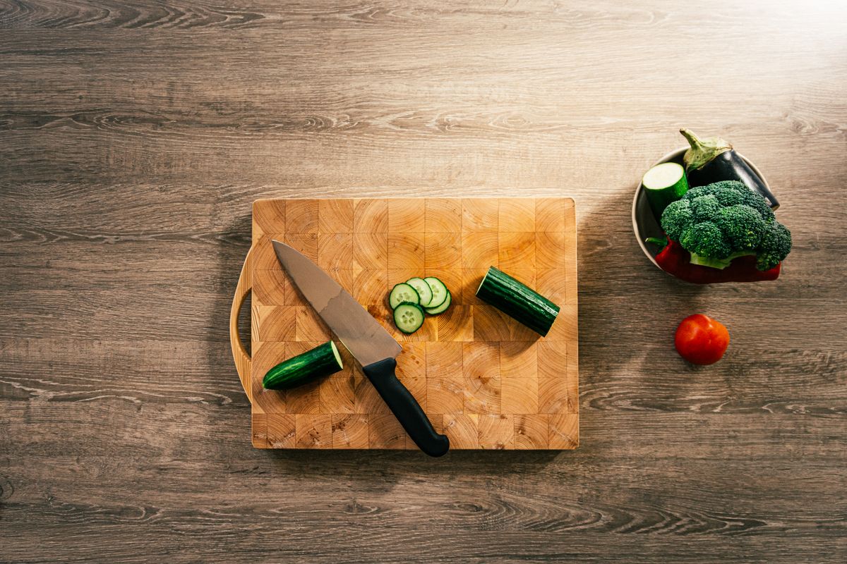 Top-down view of fresh vegetables and knife on wooden board, perfect for healthy lifestyle concepts.