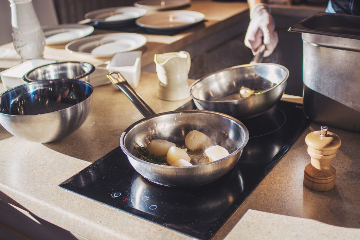Chef preparing delicious scallops with herbs in modern kitchen setting. Culinary art captured indoors.
