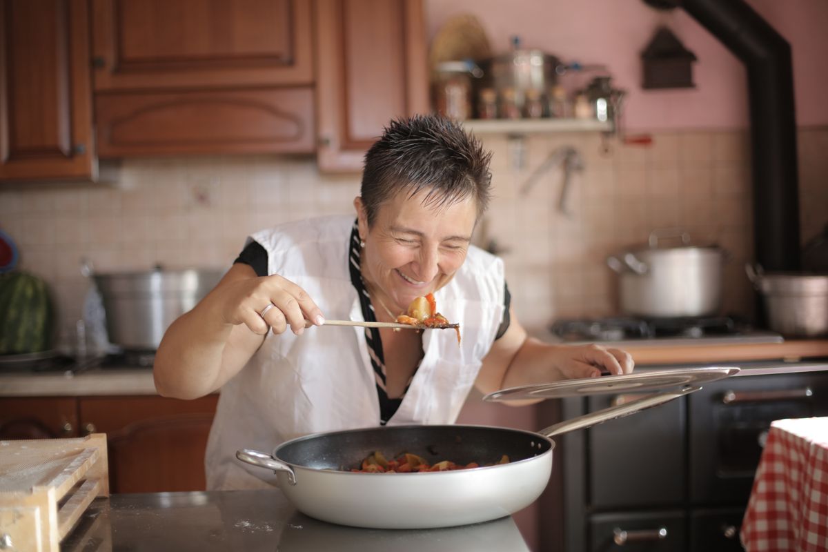 A cheerful woman savoring the aroma of a freshly cooked meal in a home kitchen.