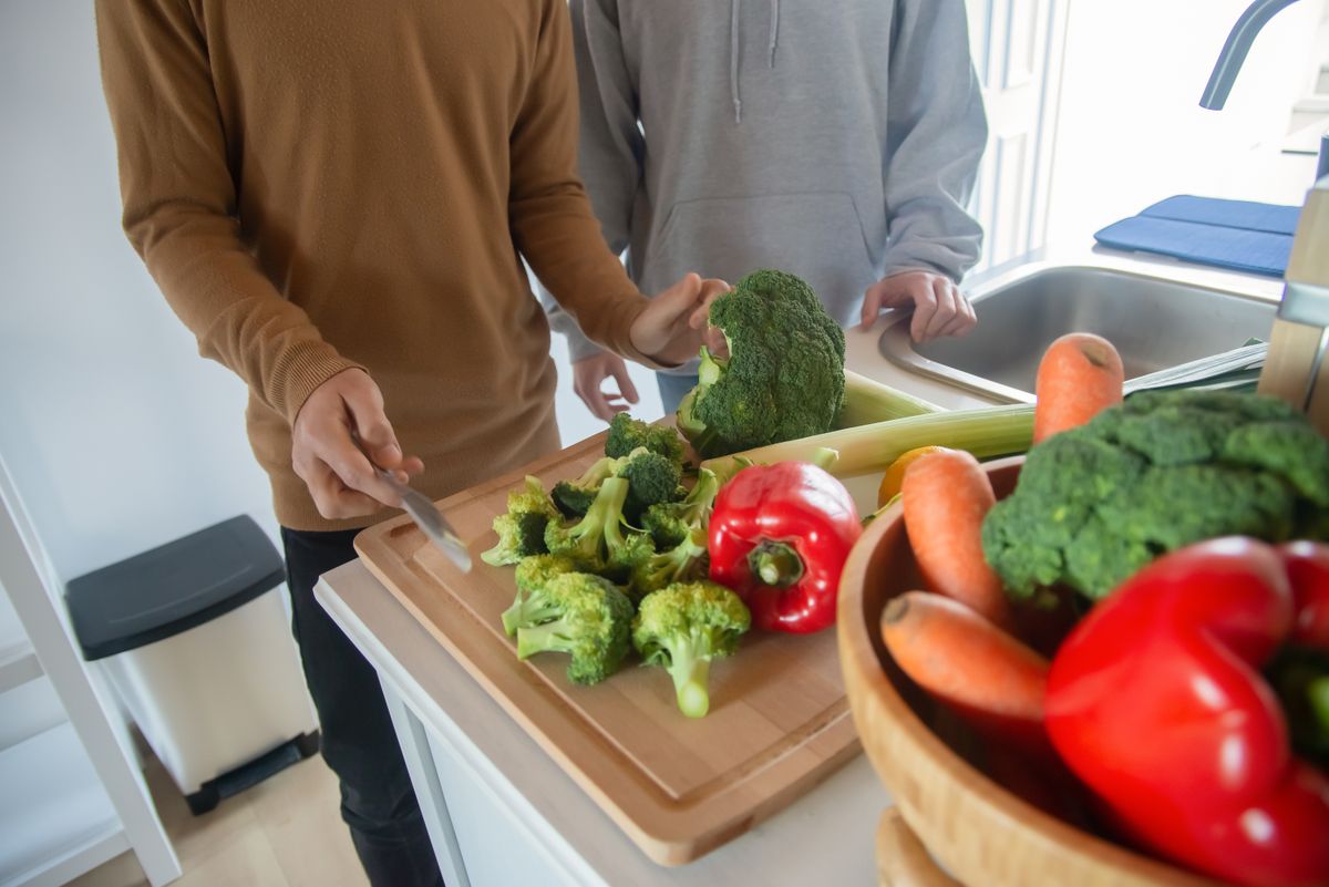 Two people preparing fresh vegetables in a kitchen, highlighting healthy eating.