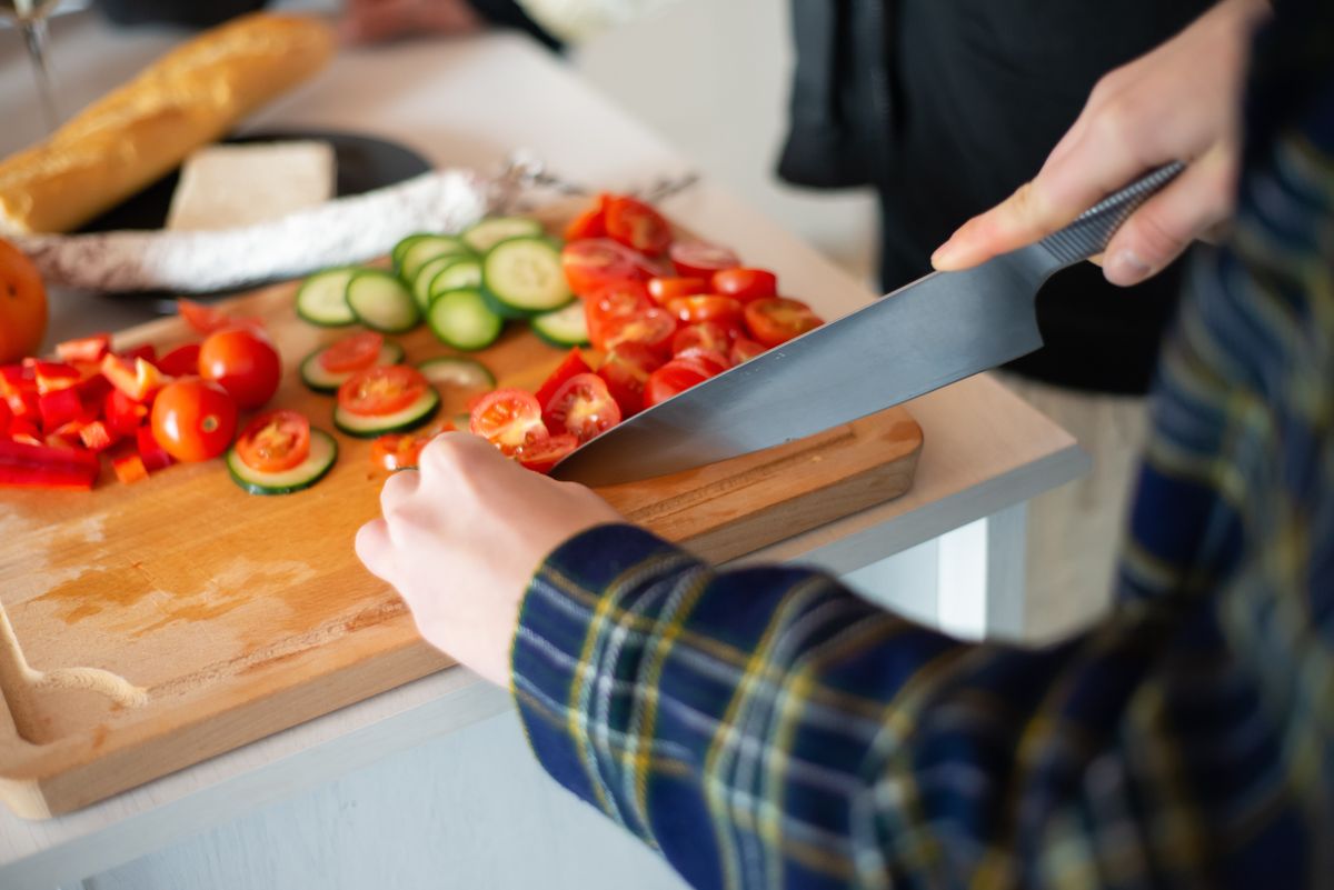 Cutting fresh vegetables for a healthy salad, showcasing tomatoes, cucumbers, and peppers.