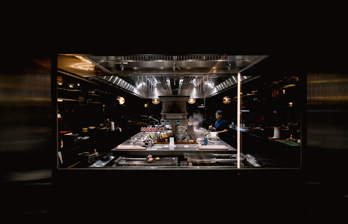 A chef working in a modern industrial kitchen setup at nighttime.