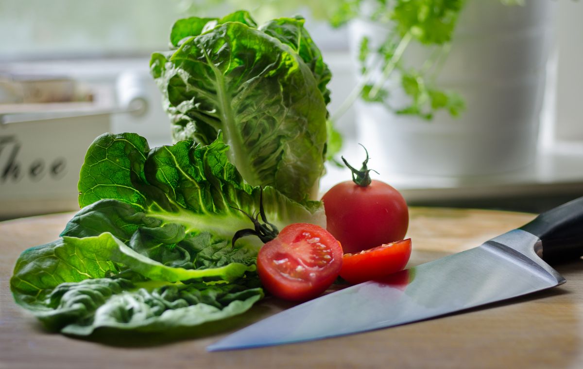 Close-up of lettuce, tomatoes, and knife on a kitchen counter, perfect for food preparation imagery.