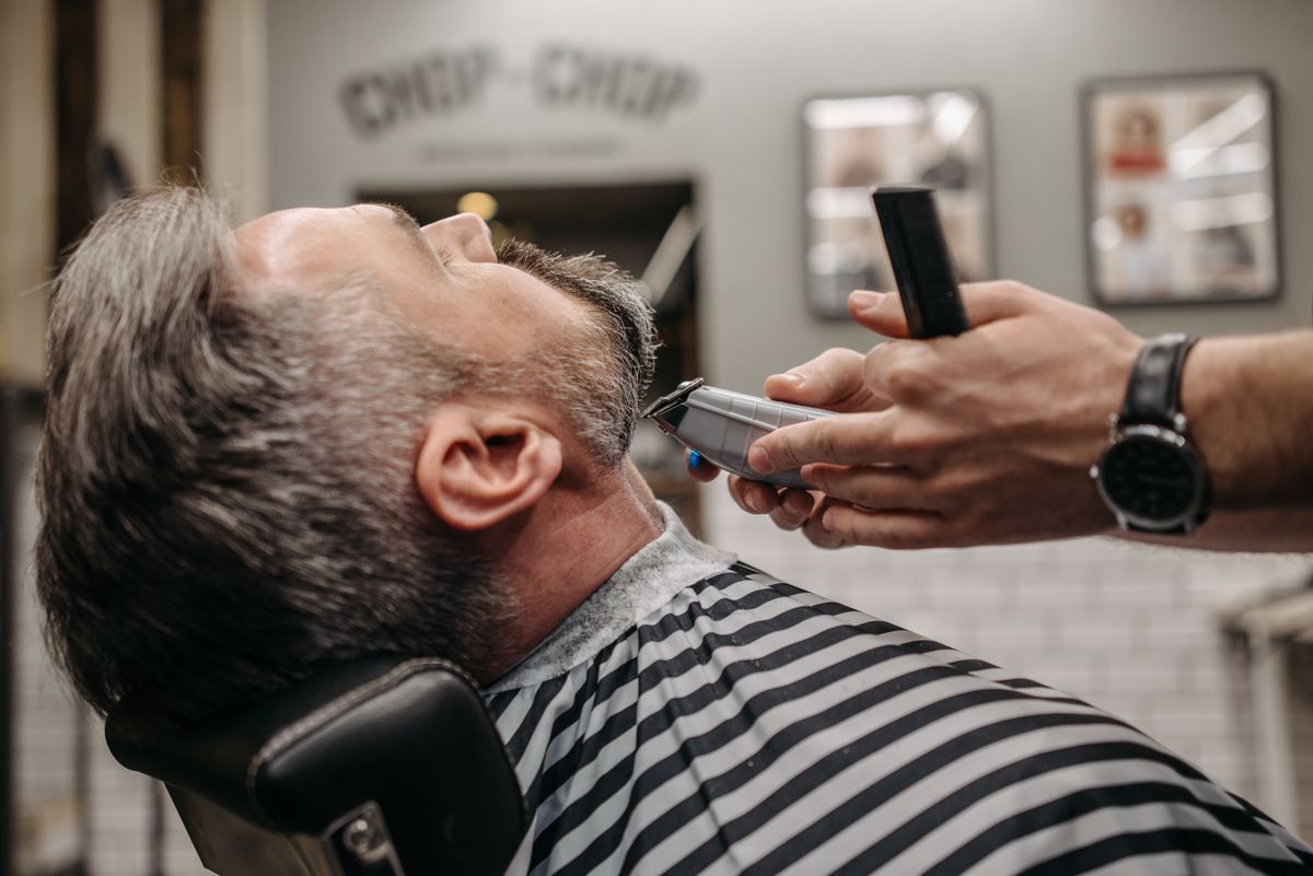 Close-up of a man getting a beard trim in a stylish barbershop. Professional grooming in modern setting.