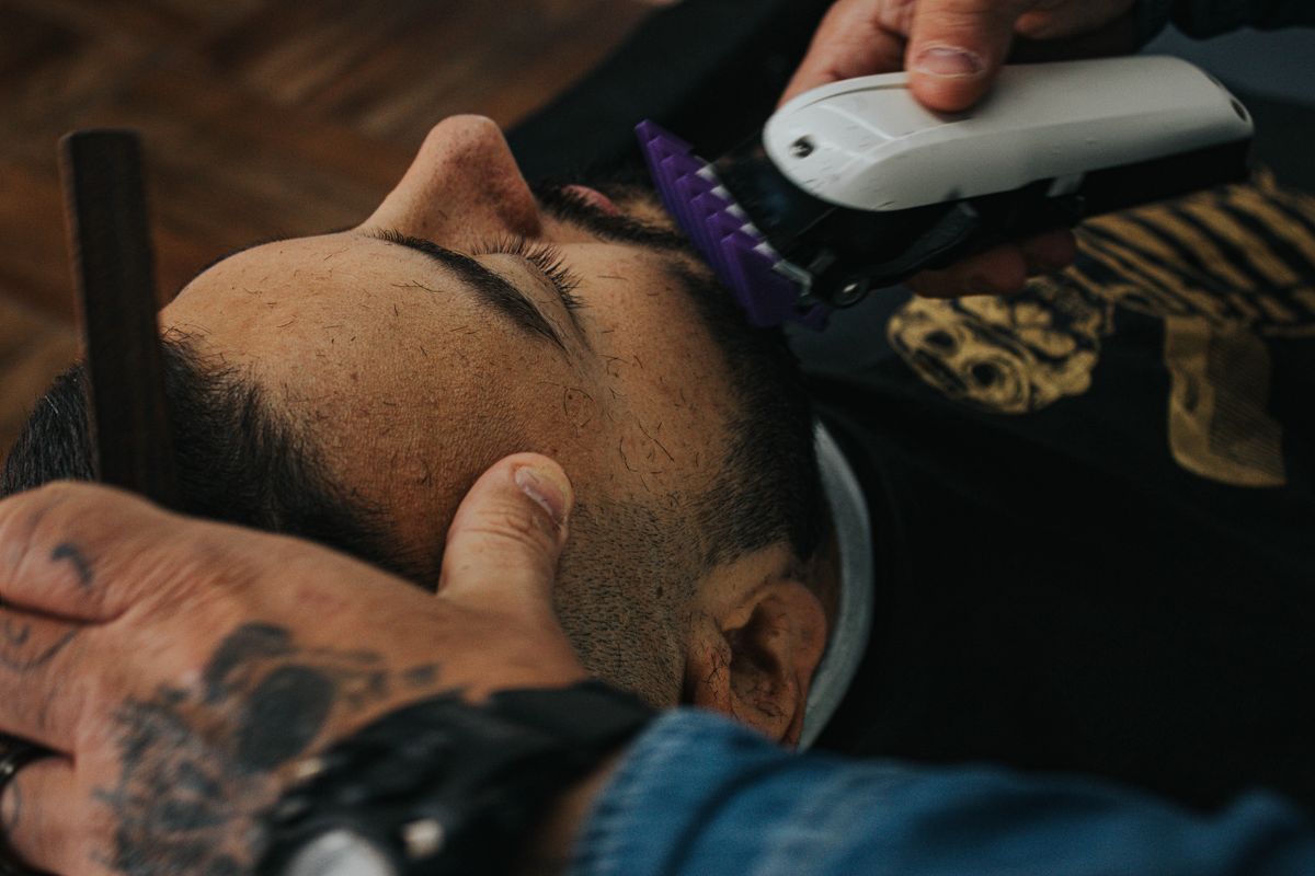 A barber skillfully shapes a beard with clippers, showcasing precision in men's grooming.