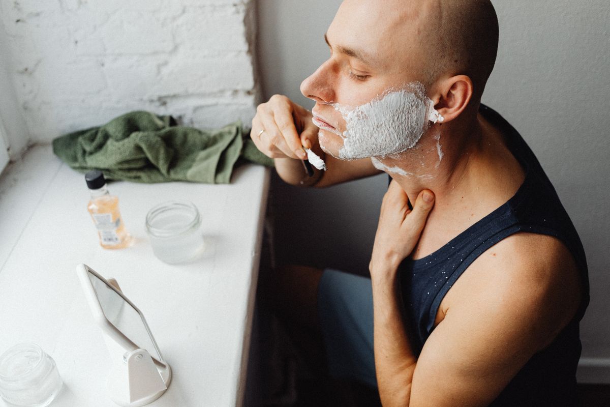 A man applying shaving cream while grooming in a bathroom at home.