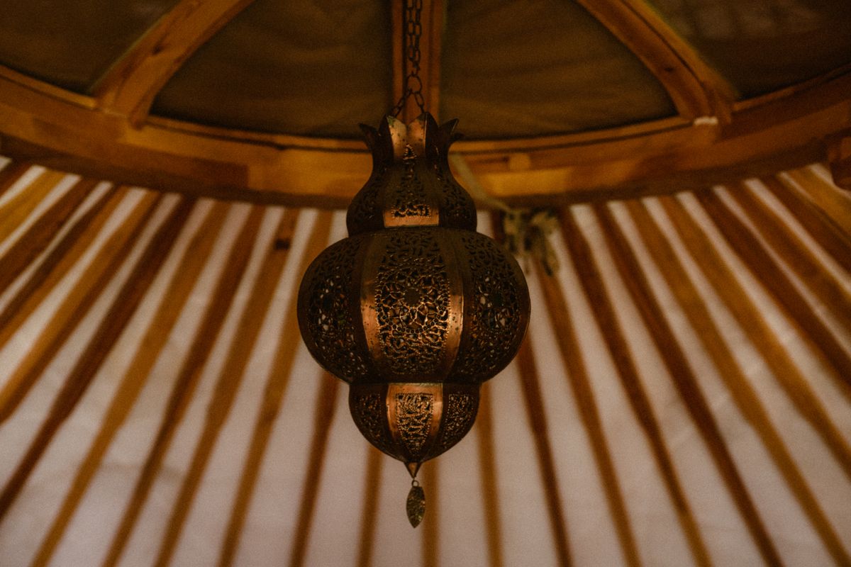 A close-up of a decorative hanging lantern inside a yurt with intricate patterns and warm lighting.