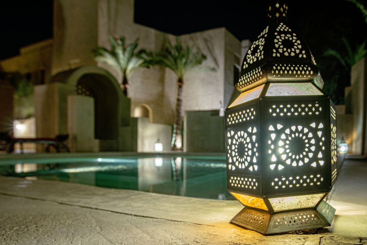 Beautifully lit traditional lantern near poolside against Dubai's stunning architecture at night.
