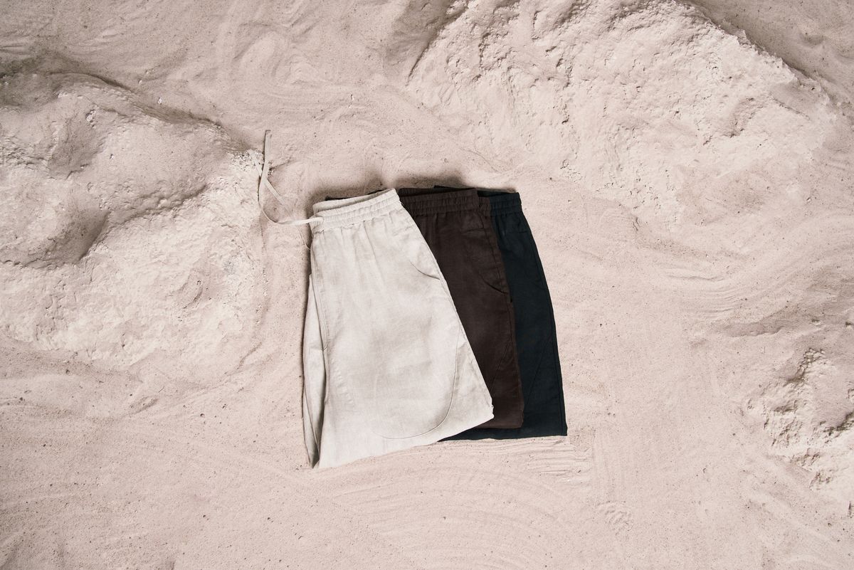 Three casual shorts displayed on sand, showcasing beachwear style.