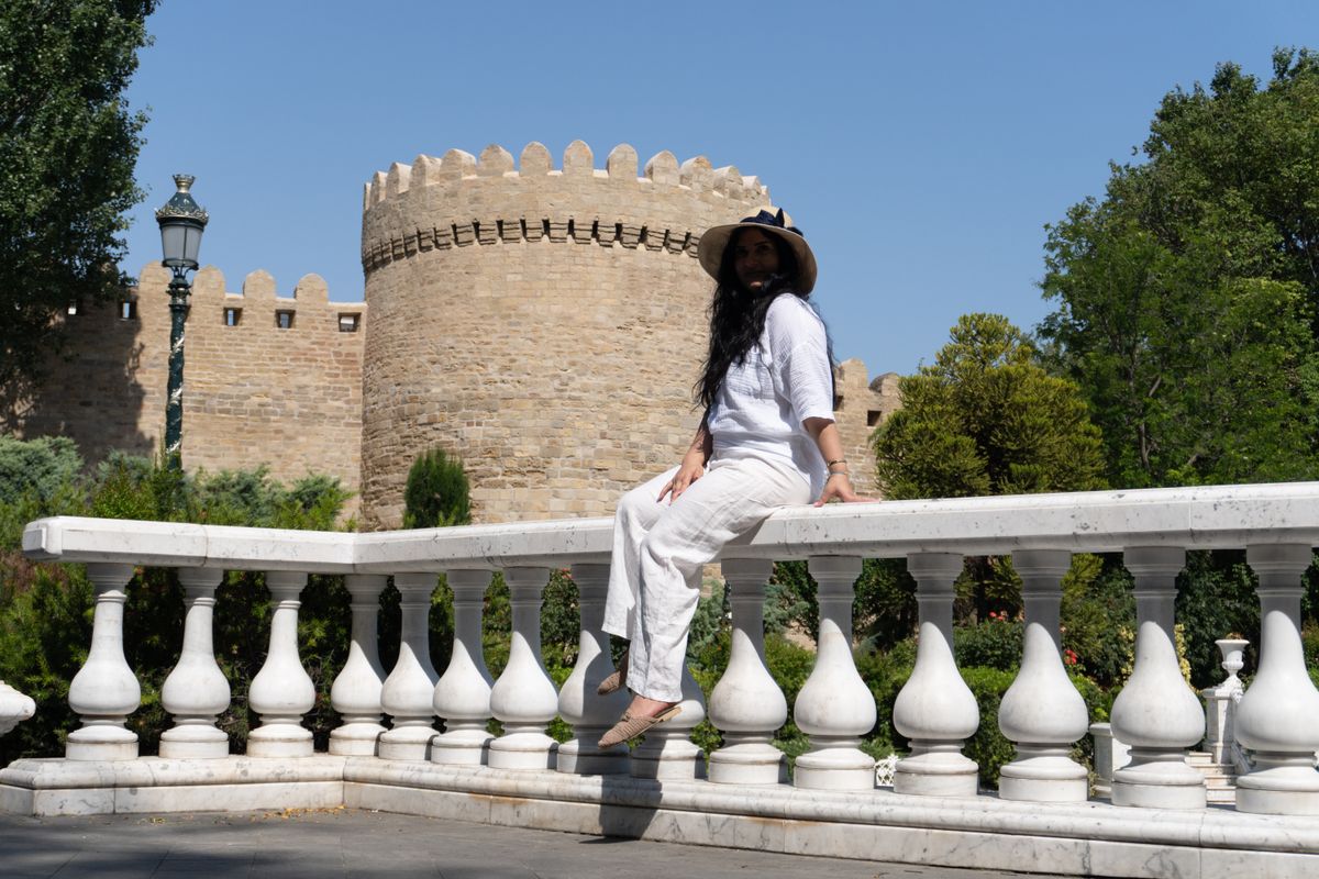 A woman in white outfit sitting by the ancient walls of Icherisheher, Baku.