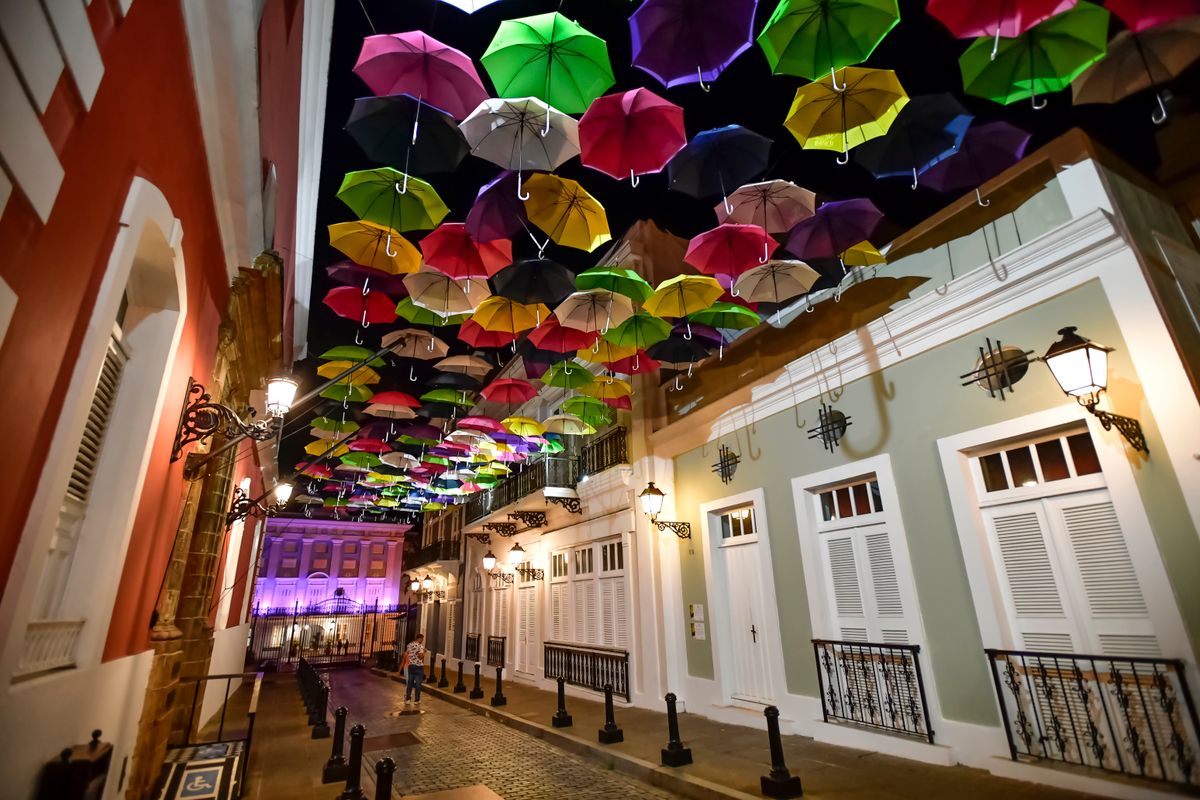 A stunning display of colorful umbrellas hanging over Calle La Fortaleza in Old San Juan, Puerto Rico, illuminated at night.