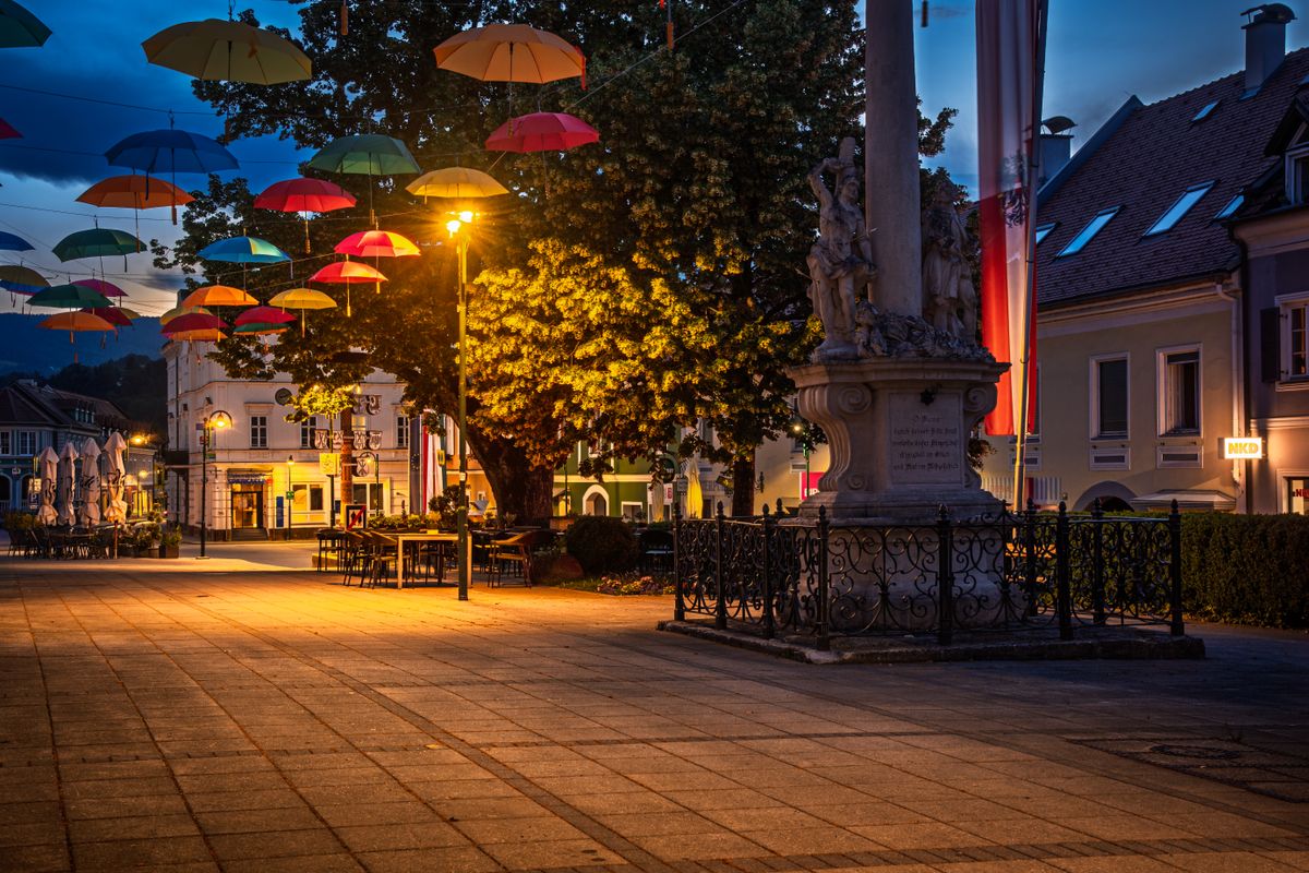 Vibrant umbrellas adorning a city square light up the night in a charming European town.