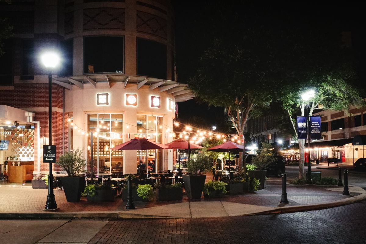 Outdoor dining at night in Sugar Land, Texas, with string lights and colorful umbrellas.